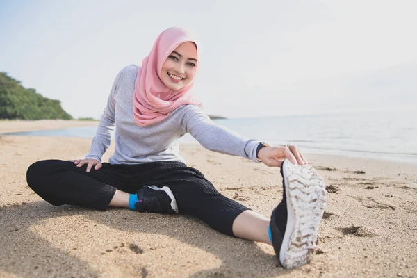 Gesunde, sportliche Frau mit Hijab lächelt, während sie Beinstretching macht — Stockfoto