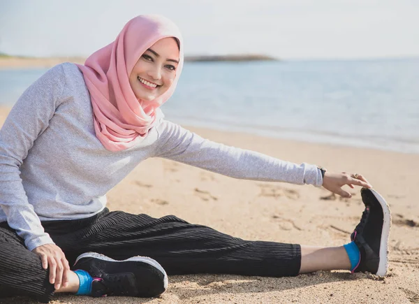 Gesunde, sportliche Frau mit Hijab lächelt, während sie Beinstretching macht — Stockfoto