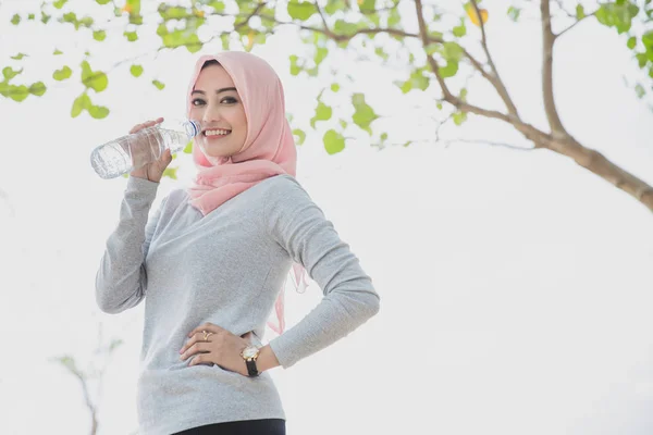 Mujer deportiva usando hijab beber agua mineral después de trotar —  Fotos de Stock