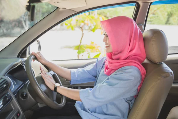 asian woman wearing hijab driving a car and hit the horn