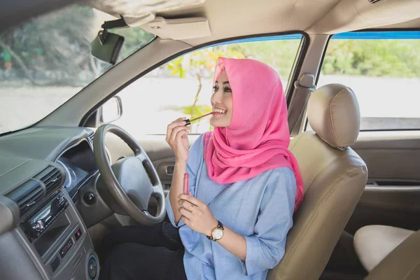 Mooie vrouw het dragen van hijab toepassing van lippenstift in de auto — Stockfoto