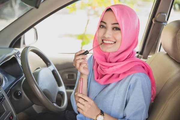 Красивая женщина носит хиджаб, нанося помаду в машине — стоковое фото