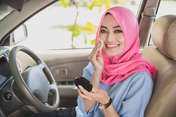 Красивая женщина улыбается, нанося порошок на лицо в машине — стоковое фото
