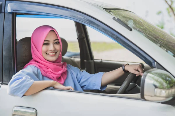 Красивая женщина в хиджабе улыбается во время вождения автомобиля — стоковое фото