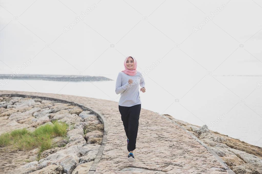asian sporty woman wearing hijab jogging at the jogging track