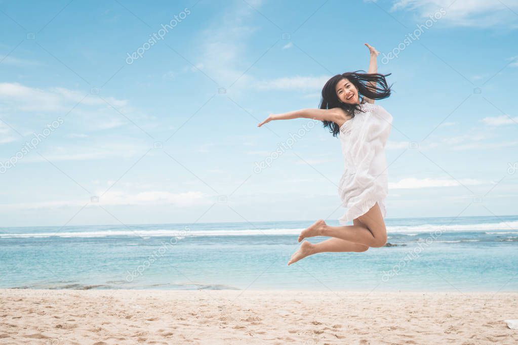 excited woman jumping on beach 