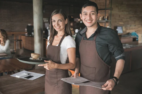 Две официантки улыбаются на камеру в кафе — стоковое фото
