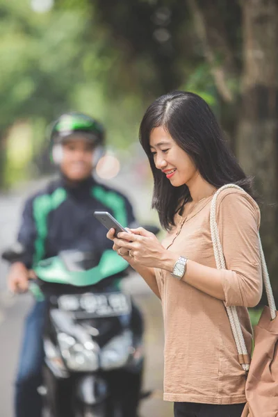 Vrouw commerciële motorfiets taxi bestellen — Stockfoto