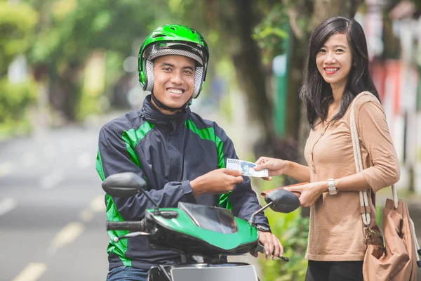 Klient płaci za jej jazdy motocykl taksówką kierowca — Zdjęcie stockowe