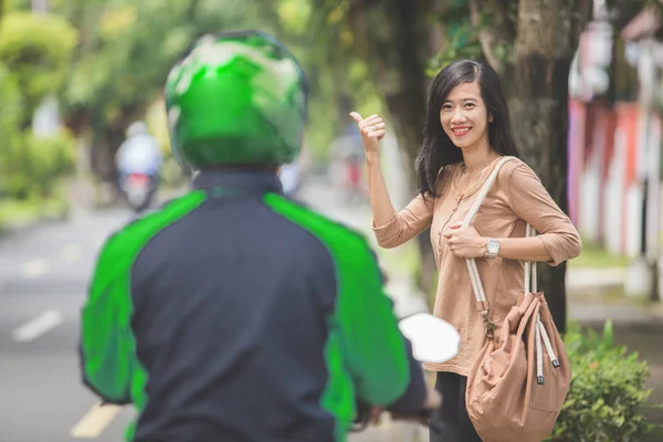 Femme debout sur le trottoir commander taxi moto en agitant il — Photo