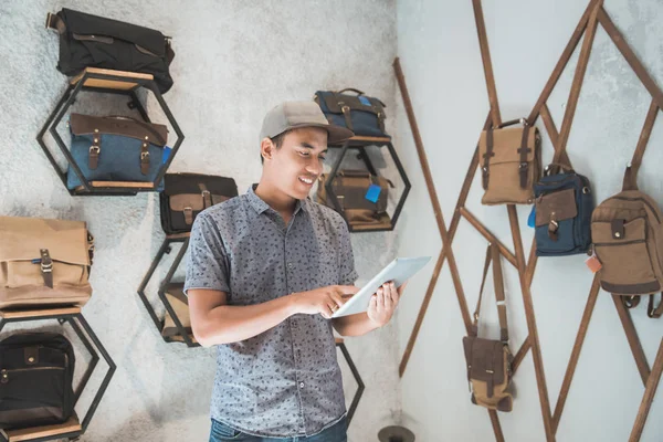 Aziatische mannelijke ondernemer in een tas winkel met tablet — Stockfoto