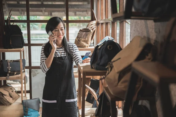 De eigenaar van het bedrijf in gesprek met mobiele telefoon in haar mode winkel — Stockfoto