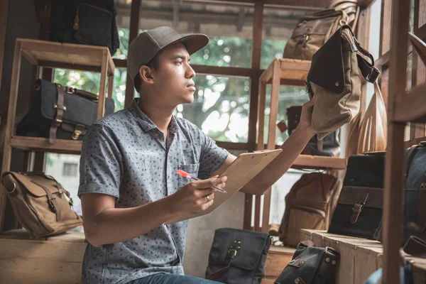 Business ägare kontrollera kvaliteten på hans produkten väska butiken — Stockfoto