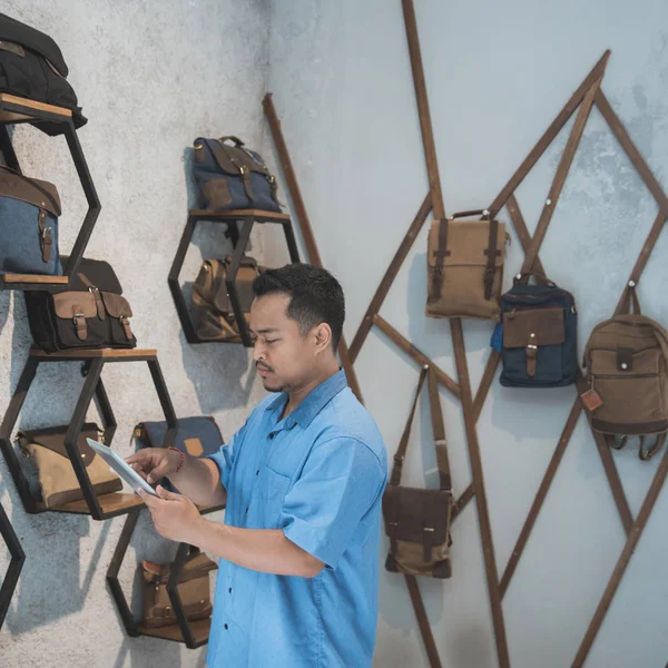 Asiatischer männlicher Geschäftsinhaber in einem Taschenladen mit Tablet — Stockfoto