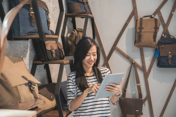 Mooie jonge ondernemer in een tas winkel met tablet — Stockfoto