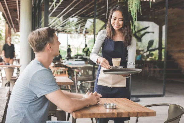 Waitress serving coffee to a customer — Stock Photo, Image