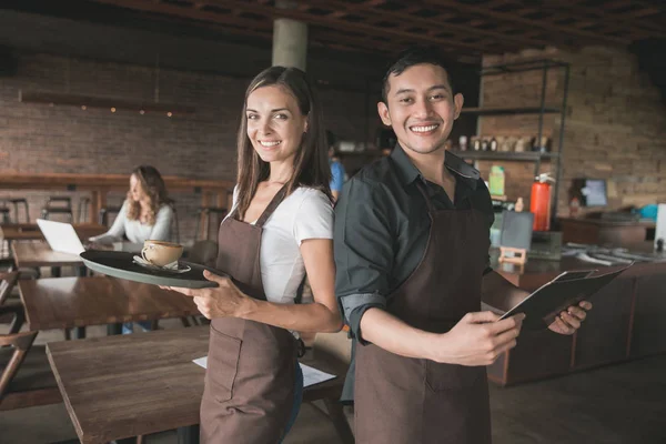 Mannelijke en vrouwelijke serveerster serveren koffie — Stockfoto