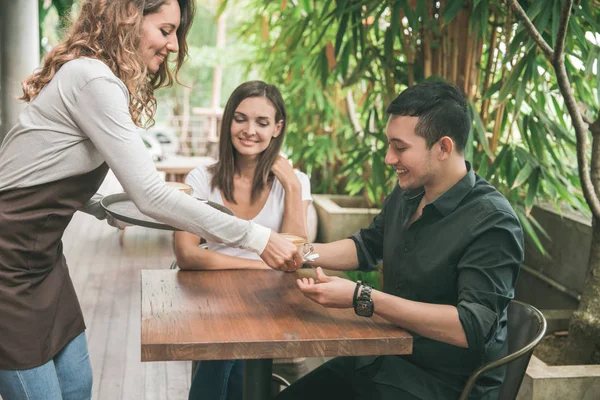 Официантка, подающая кофе для пары клиентов — стоковое фото