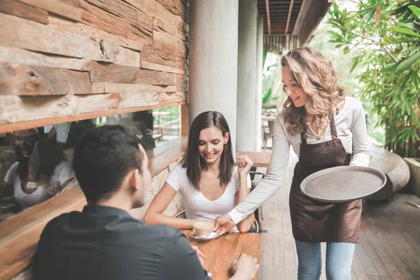 Servitrisen serverar kaffe till kunder — Stockfoto