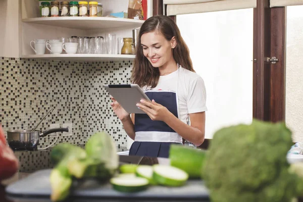 Frau liest beim Kochen auf Tablet — Stockfoto