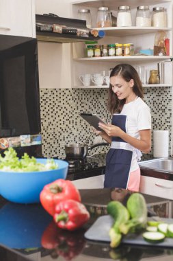 Kadın yemek yaparken tablet üzerinde okuma