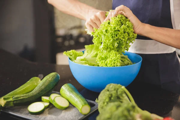 Kadın salata için sebze hazırlıyor.