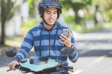 Motosiklet üzerinde akıllı telefon kullanan adam