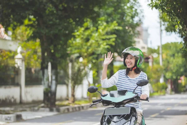 Kobieta na motocyklu, macha ręką — Zdjęcie stockowe