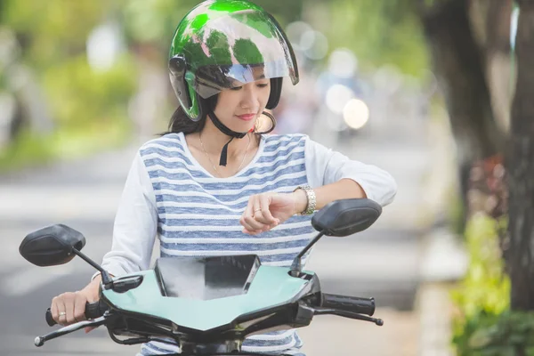 Woman looking at watch on motorbike — Stock Photo, Image