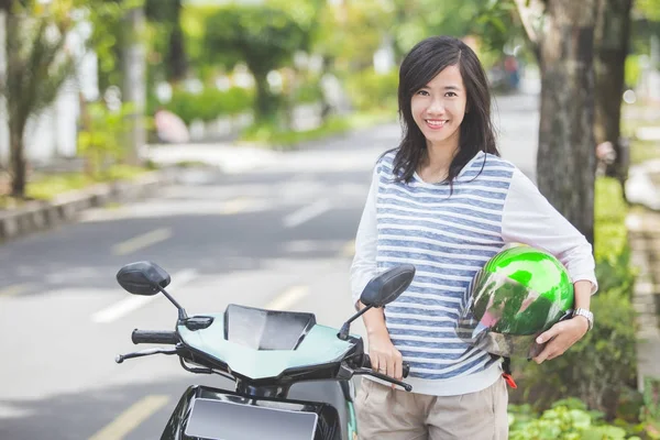 Mujer sonriente de pie junto a la moto —  Fotos de Stock