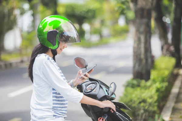 Kobieta za pomocą smartfona na motocykl — Zdjęcie stockowe