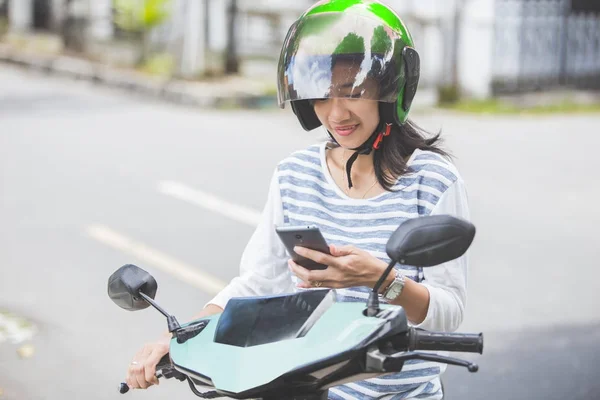 在摩托车上使用智能手机的女人 — 图库照片