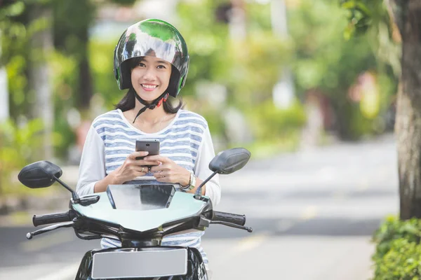 Frau nutzt Smartphone auf Motorrad — Stockfoto