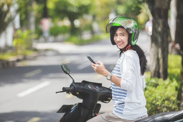 Mulher usando smartphone na moto — Fotografia de Stock