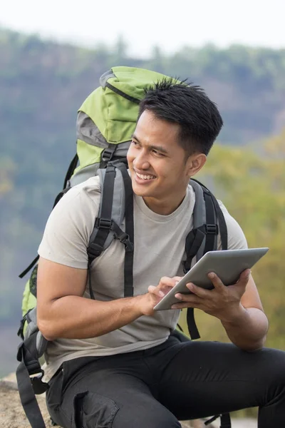 Hombre excursionista usando tableta y sonriendo —  Fotos de Stock