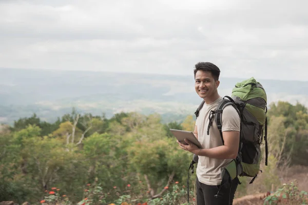 Hombre excursionista usando tableta y sonriendo — Foto de Stock