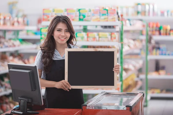 Cashier with blank blackboard standing — Stock Photo, Image