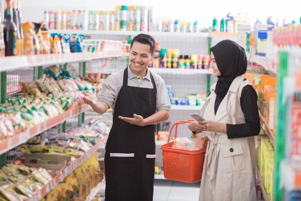 Affärsinnehavaren hjälper muslimska kvinnliga kunden — Stockfoto