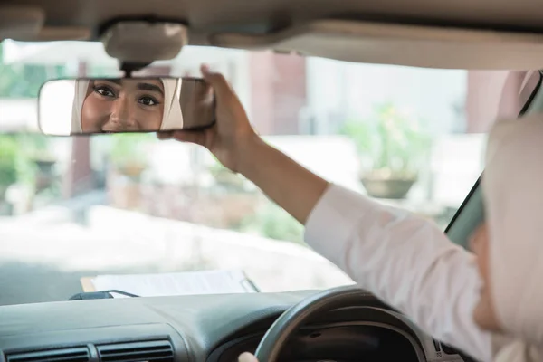 Женщина регулирует свое зеркало автомобиля — стоковое фото