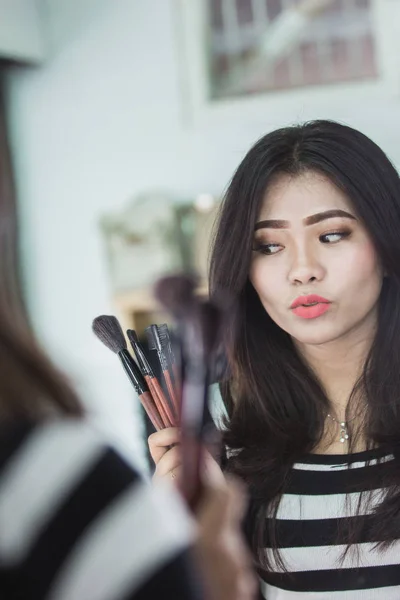 Mujer mirando maquillaje cepillos —  Fotos de Stock