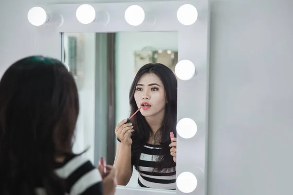 asian woman applying lipstick