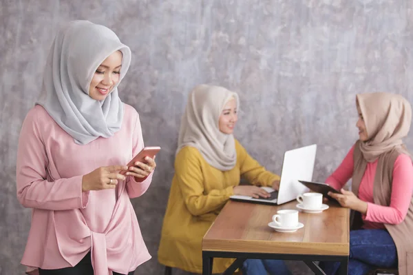 Красивая мусульманская женщина улыбается и держит мобильный телефон в то время как он — стоковое фото
