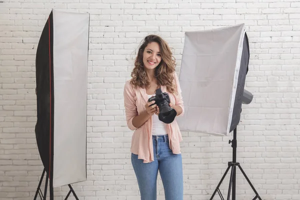 Junge Fotografin im Studio mit Beleuchtung am beackgr — Stockfoto