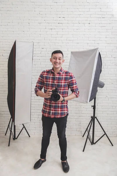 Young photographer in studio with lighting at the beackground — Stock Photo, Image