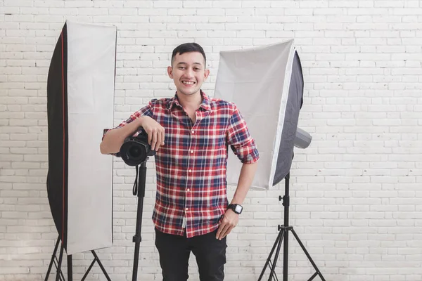 Young photographer with camera in professionally equipped studio — Stock Photo, Image
