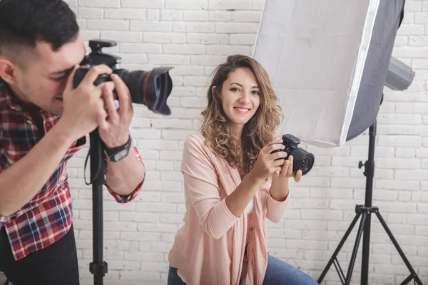 Genç kadın fotoğrafçı fotoğraf makinesi, onun ortağı t süre bakarak — Stok fotoğraf