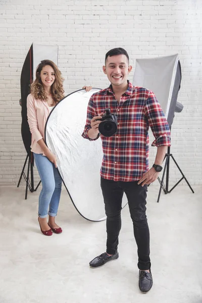 Jonge fotograaf met zijn mooie assistent in studio — Stockfoto