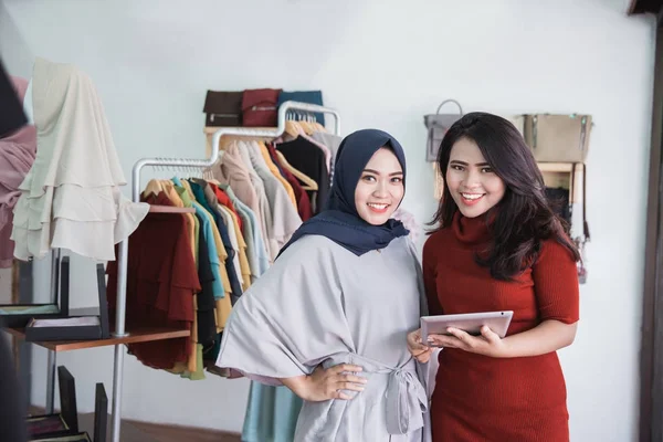 fashion shop owner and her assistant using tablet in fashion sto