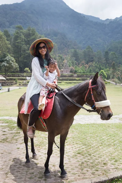 Criança com a mãe unidade no topo do cavalo — Fotografia de Stock