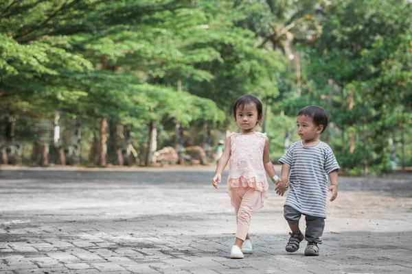 Niño y niña caminando juntos y tomados de la mano — Foto de Stock